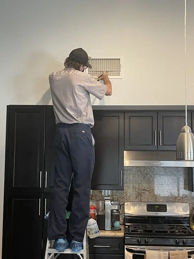 Technician inspecting an air vent during HVAC service in Boxford